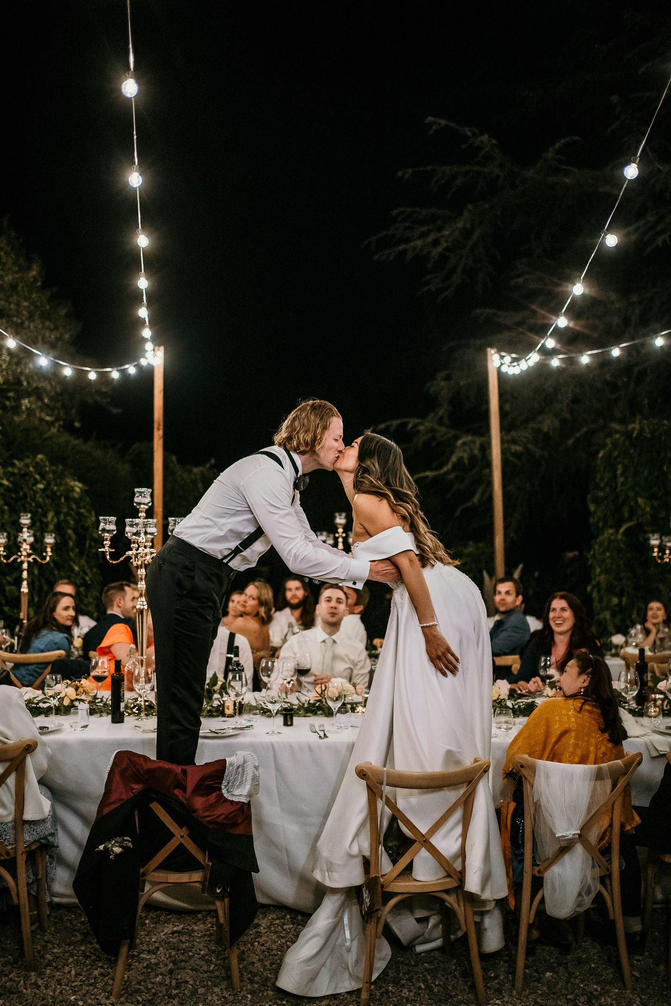 Bride and groom kissing, photographed by their wedding photographer during a romantic wedding dinner in ITaly