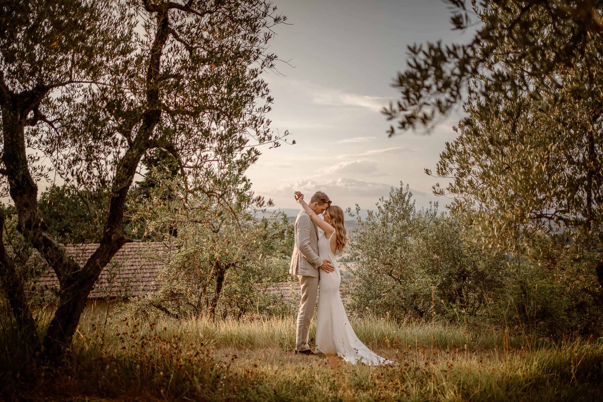 couple kissing in an olive grove at their destination wedding in Tuscany